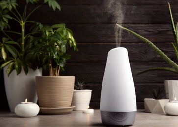 Photo of Composition with modern aroma humidifier on table against dark wooden background, space for text