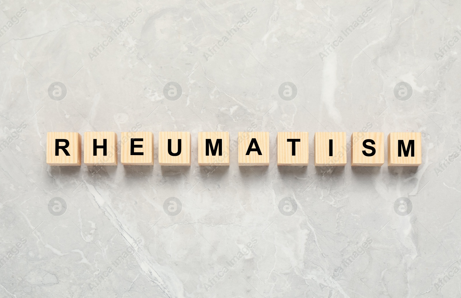 Photo of Word Rheumatism made of cubes on light gray marble table, top view