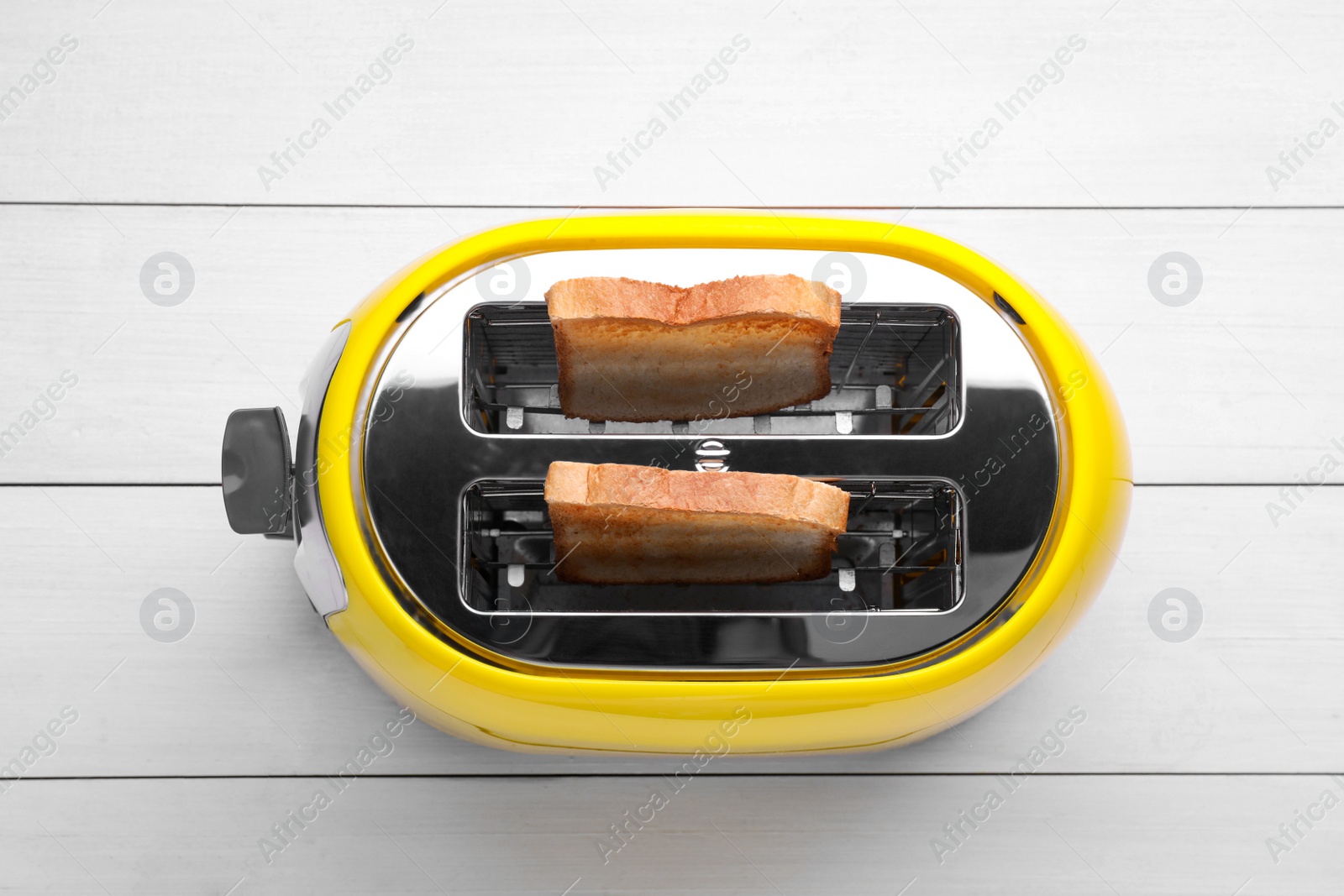 Yellow toaster with roasted bread on white wooden table, top view Photo of Yellow toaster with roasted bread on white wooden table, top view