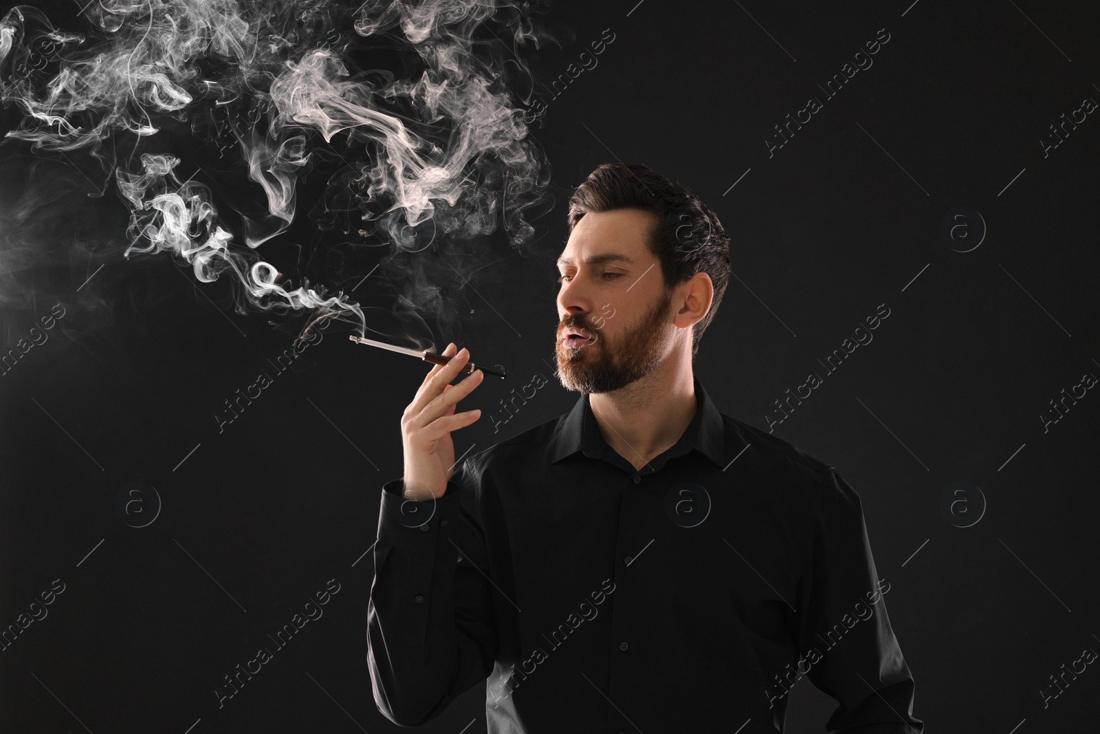 Photo of Man using cigarette holder for smoking on black background