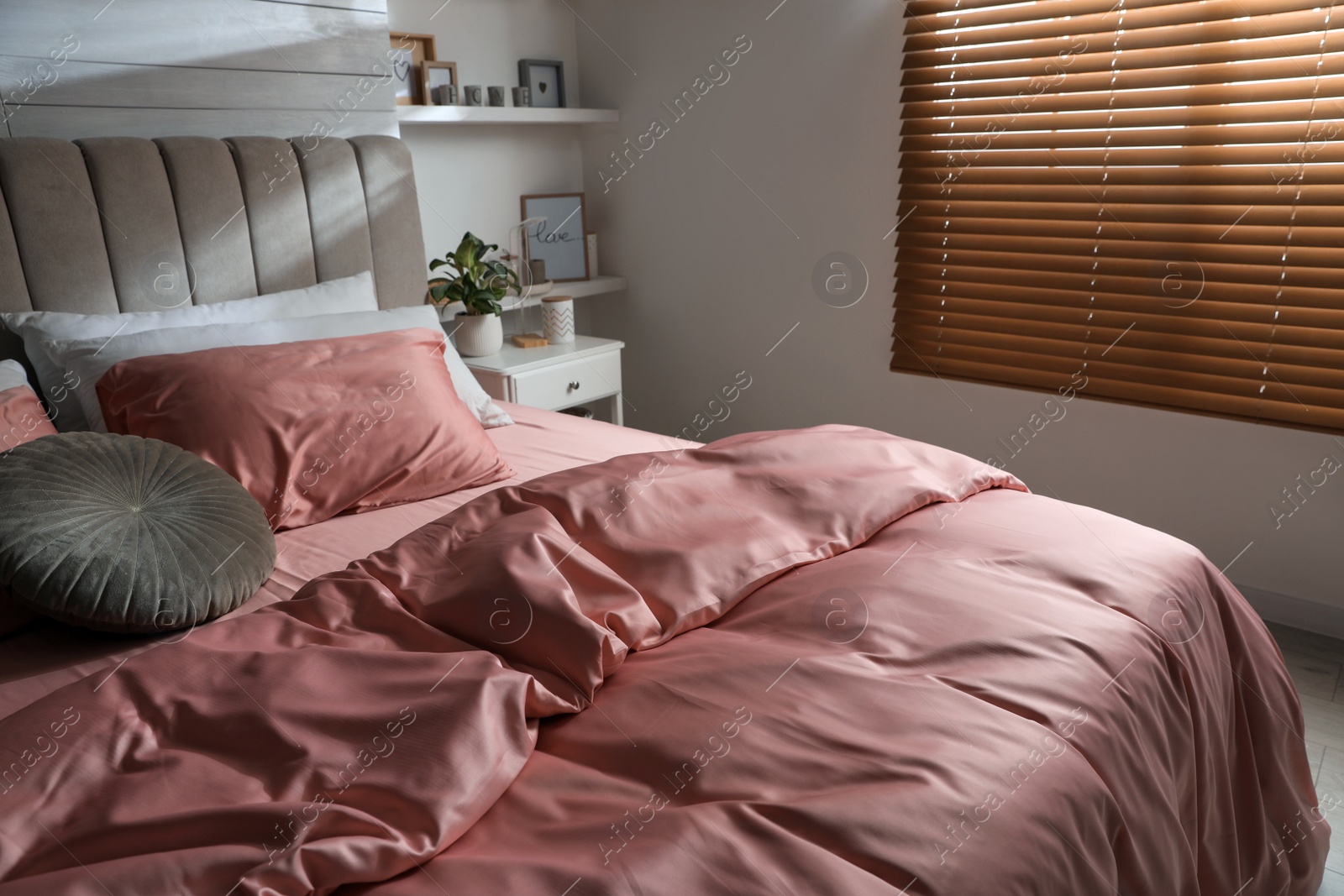 Photo of Bed with beautiful silky linens in stylish room interior