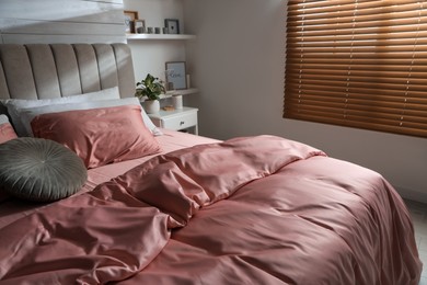 Photo of Bed with beautiful silky linens in stylish room interior