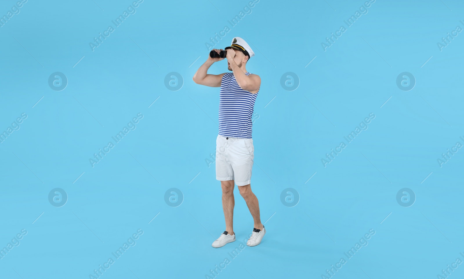 Photo of Sailor looking through binoculars on light blue background