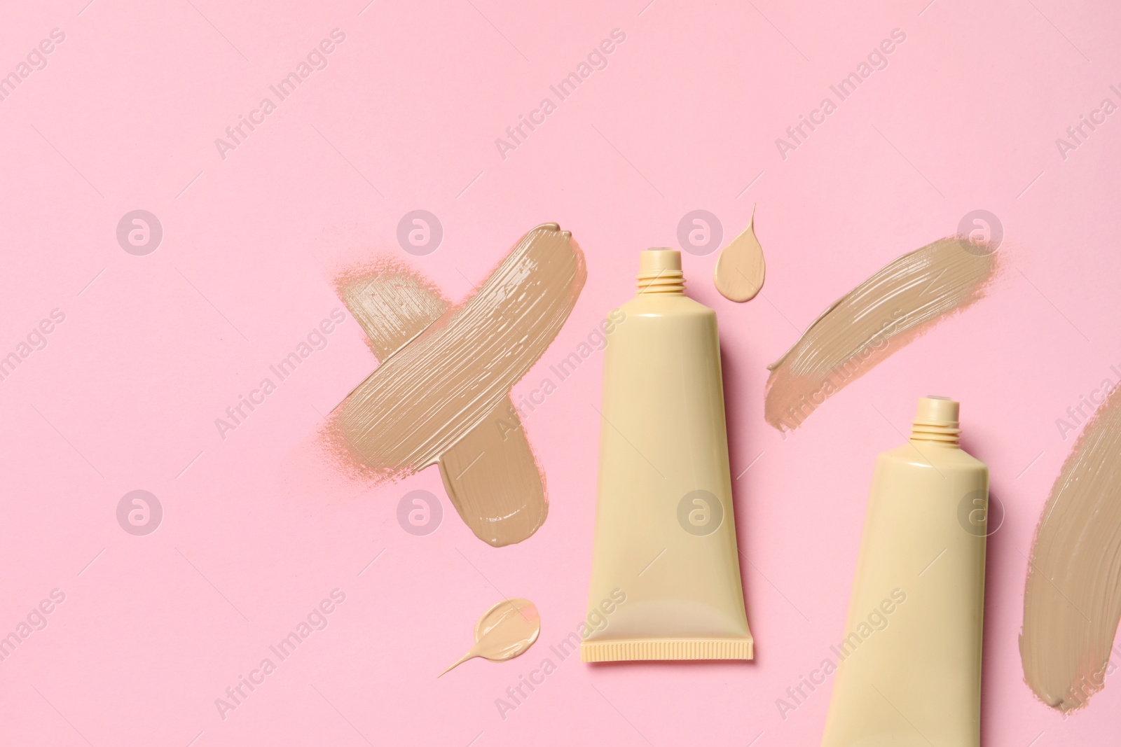 Photo of Liquid foundations and swatches on pink background, flat lay. Space for text