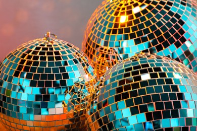 Photo of Bright shiny disco balls on color background, closeup