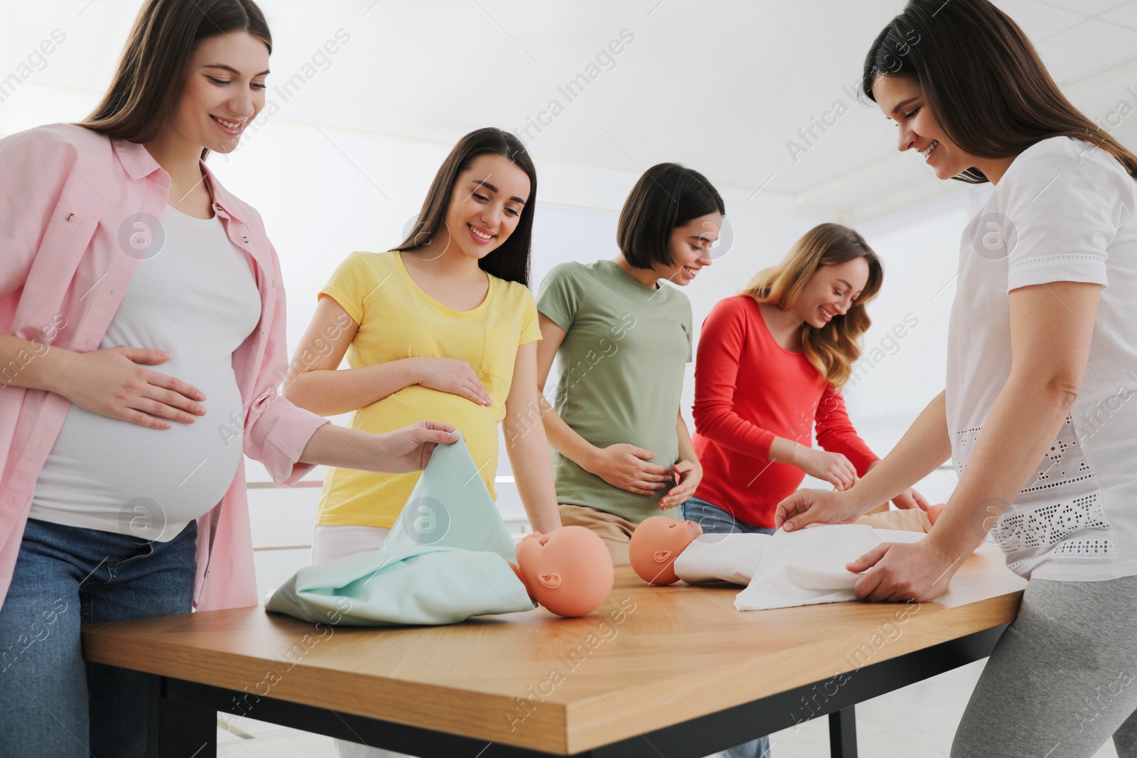 Photo of Pregnant women learning how to swaddle baby at courses for expectant mothers indoors