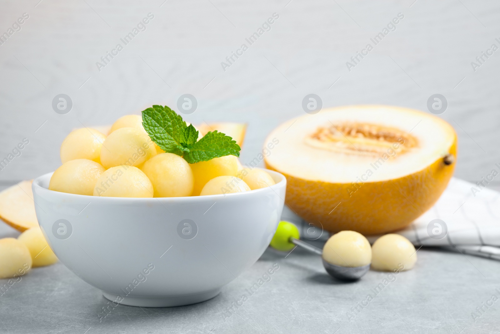 Photo of Melon balls and mint in bowl on light grey table. Space for text