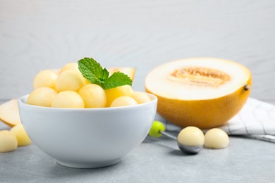 Melon balls and mint in bowl on light grey table. Space for text