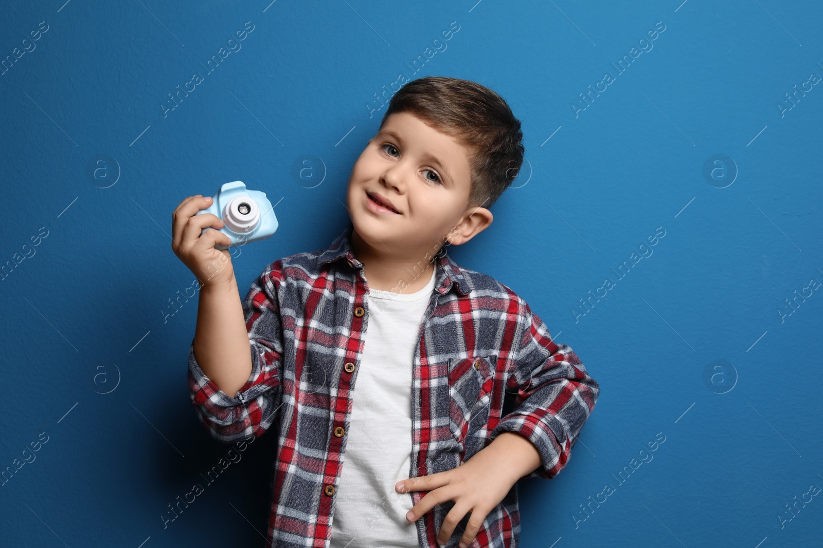 Photo of Little photographer with toy camera on blue background