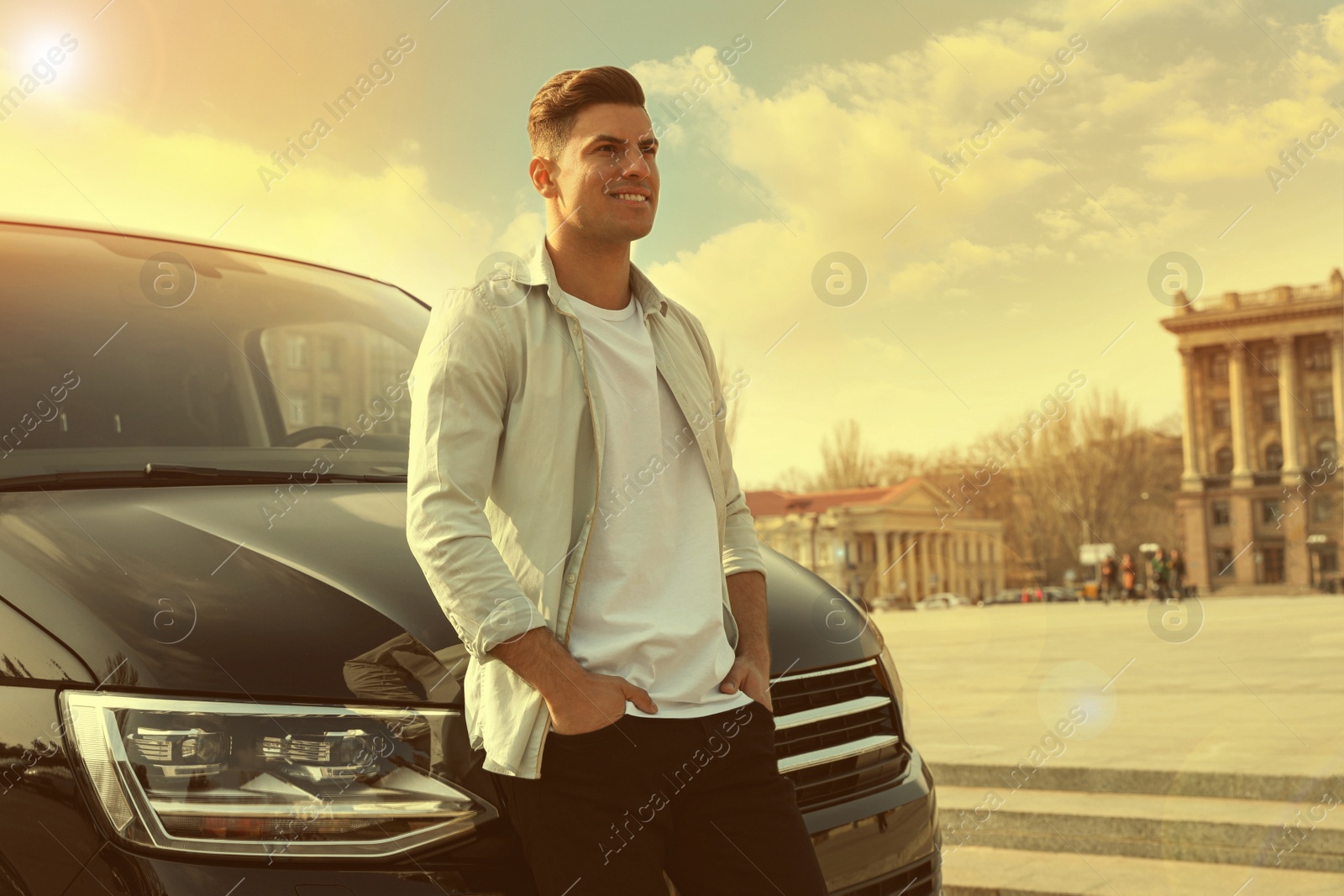 Image of Handsome man near modern car on city street