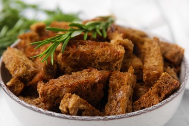 Photo of Delicious crispy rusks with rosemary in bowl, closeup view
