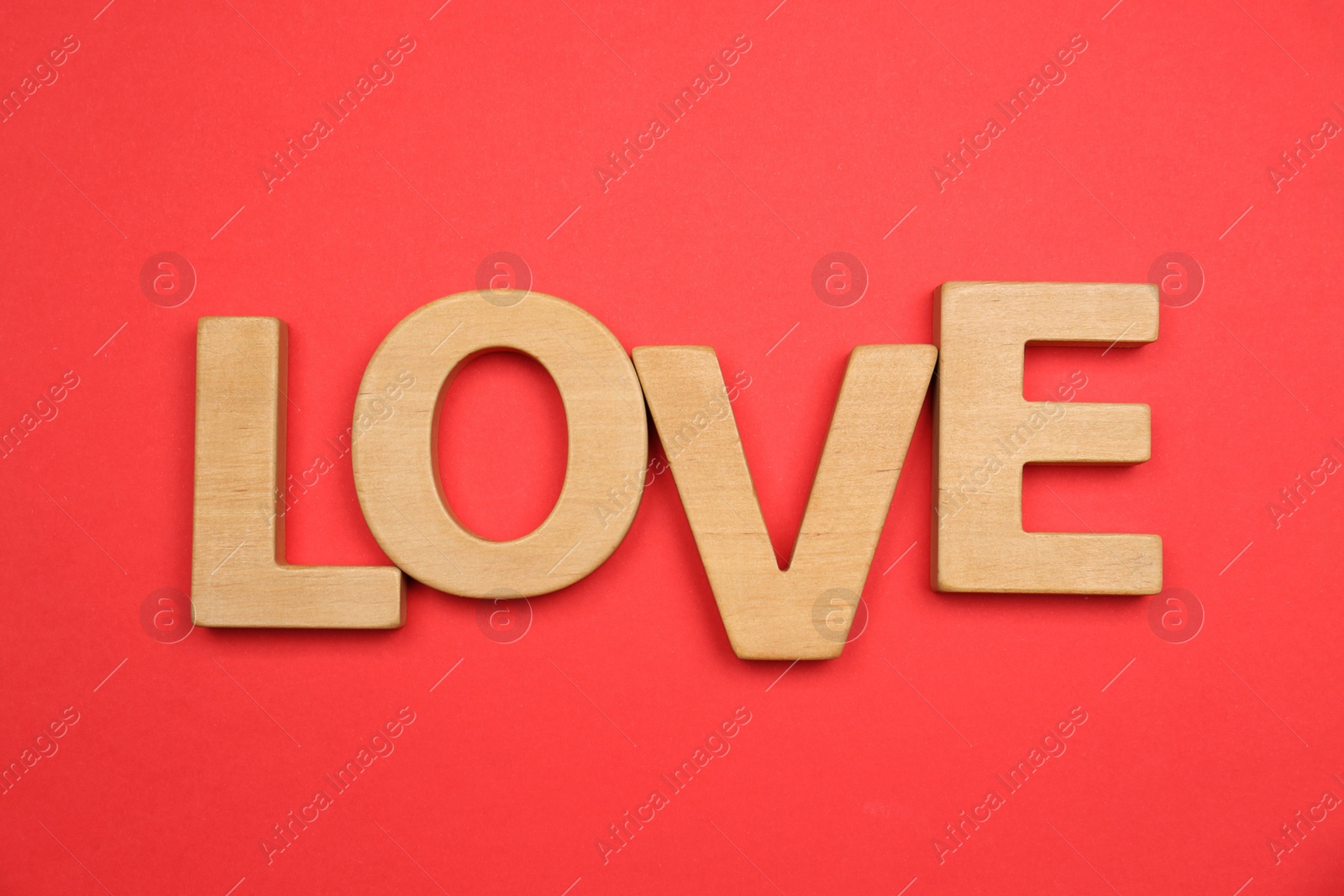 Photo of Word LOVE made of wooden letters on red background, flat lay