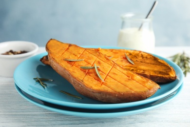 Plate with baked sweet potato on white wooden table, closeup