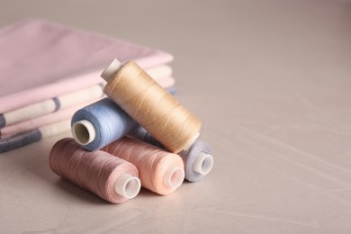 Photo of Set of color sewing threads on light grey table, space for text