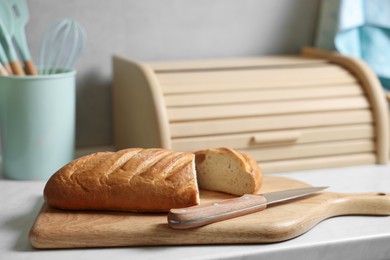 Wooden bread basket, freshly baked loaf on white marble table in kitchen