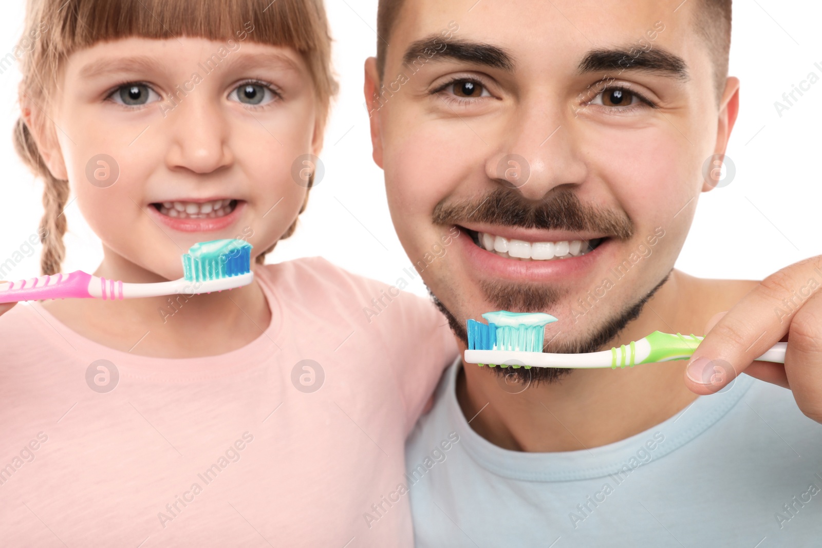 Photo of Little girl and her father brushing teeth together on white background, closeup