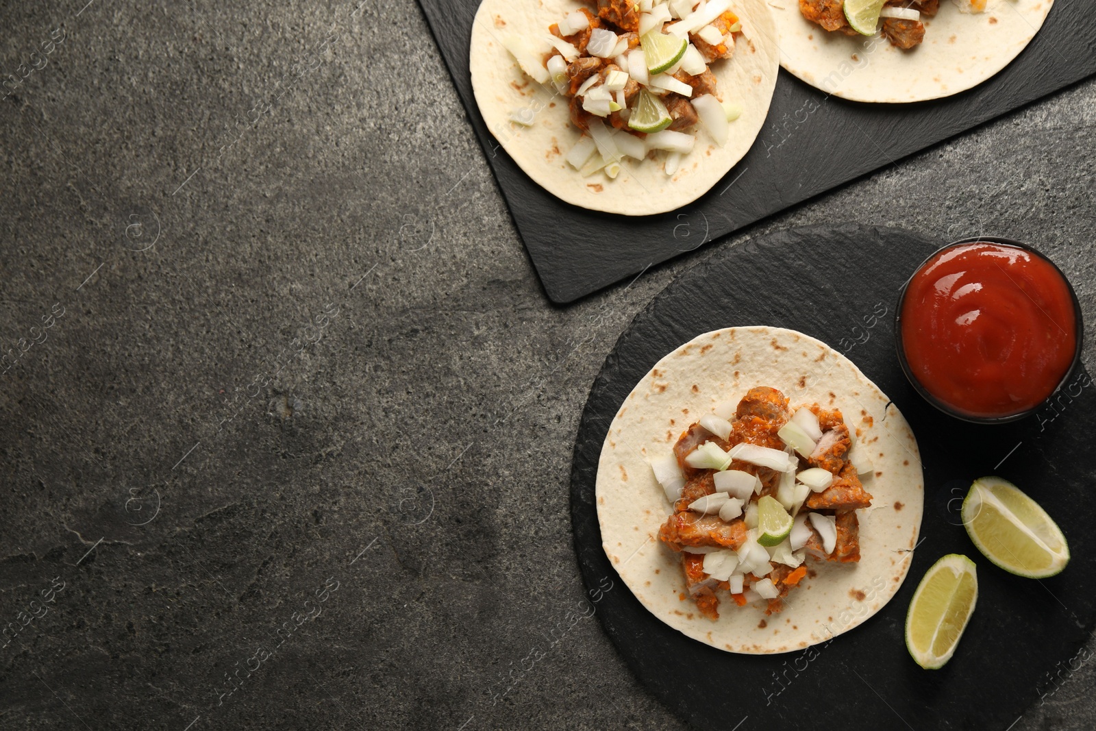 Photo of Delicious tacos with vegetables, meat and ketchup on grey textured table, flat lay. Space for text