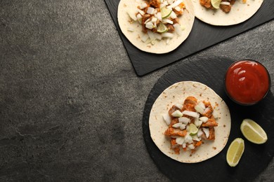 Photo of Delicious tacos with vegetables, meat and ketchup on grey textured table, flat lay. Space for text