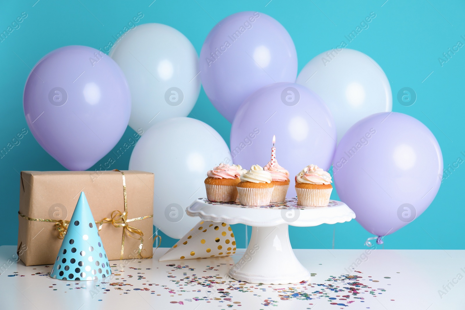 Photo of Composition with birthday cupcakes and balloons on table