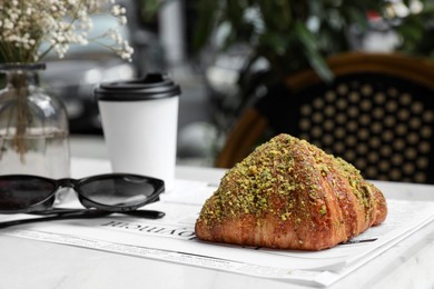 Photo of Delicious croissant, paper cup and sunglasses on white table