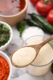 Photo of Spoon with fresh marinade over table, closeup