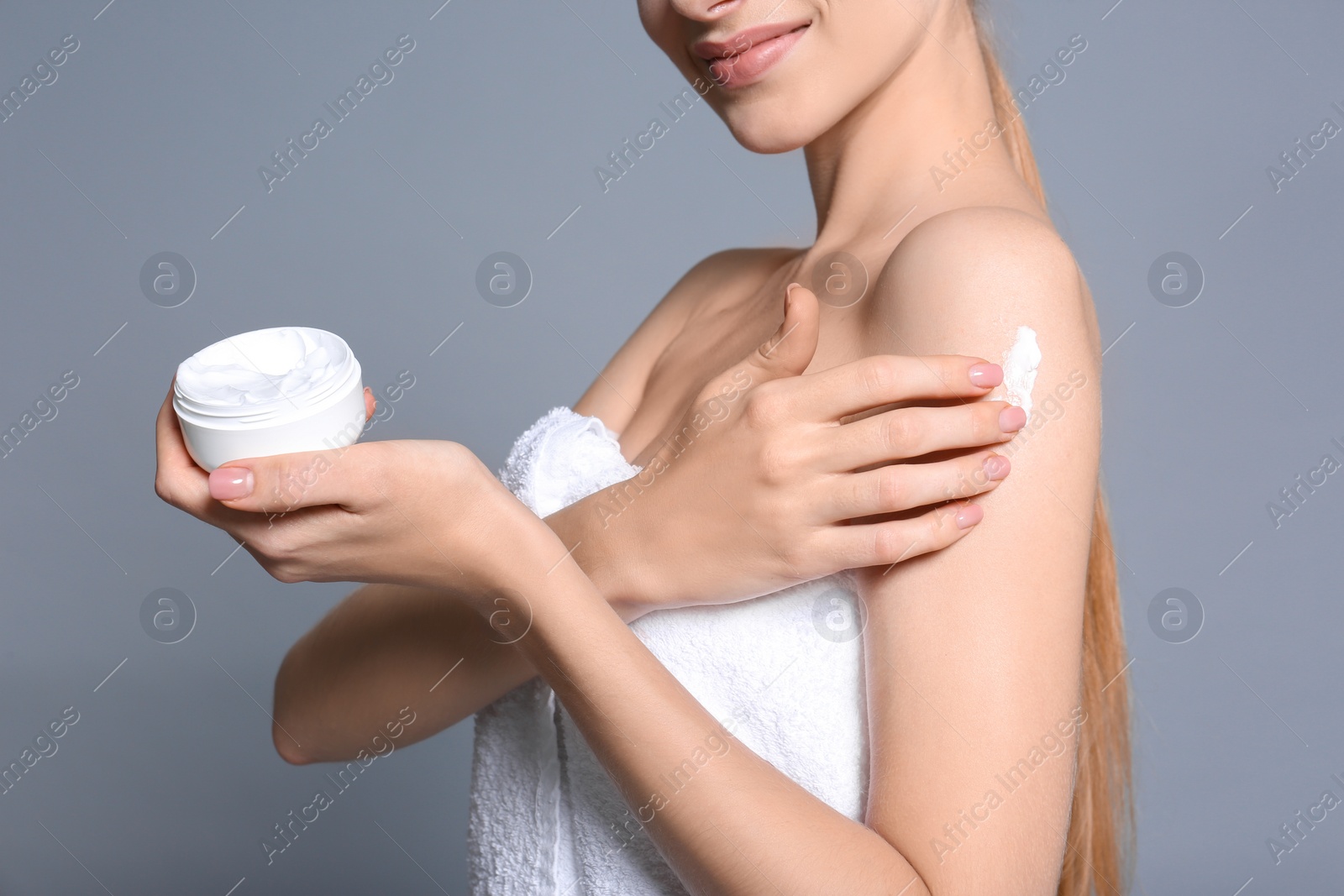 Photo of Young woman with jar of body cream on color background