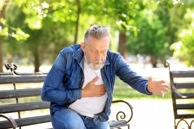 Mature man having heart attack on bench in park