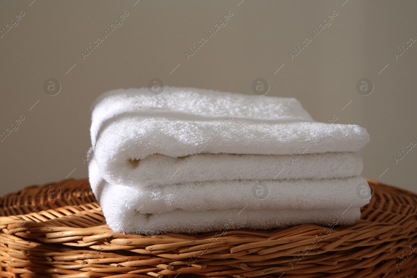 Photo of Soft terry towels on wicker basket indoors, closeup