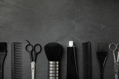 Photo of Professional tools for hair dyeing on black stone background, flat lay. Space for text