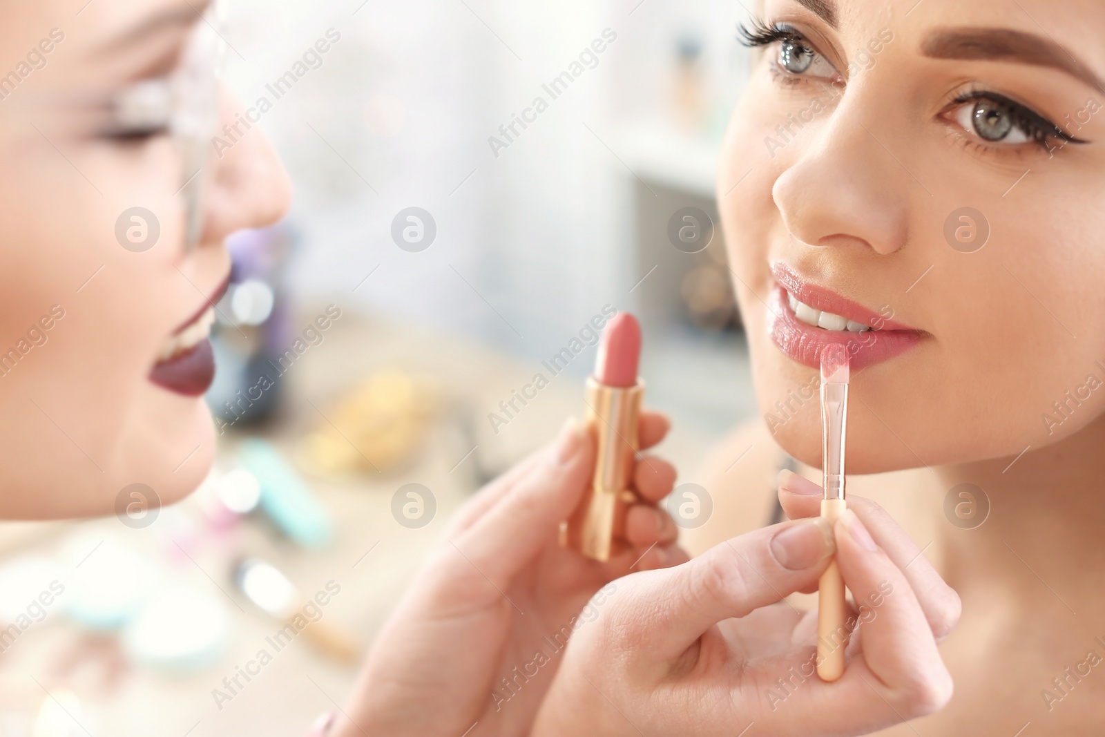 Photo of Professional makeup artist working with beautiful young woman in studio