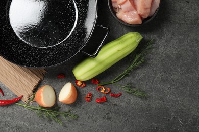 Photo of Empty iron wok and raw ingredients on grey table, flat lay