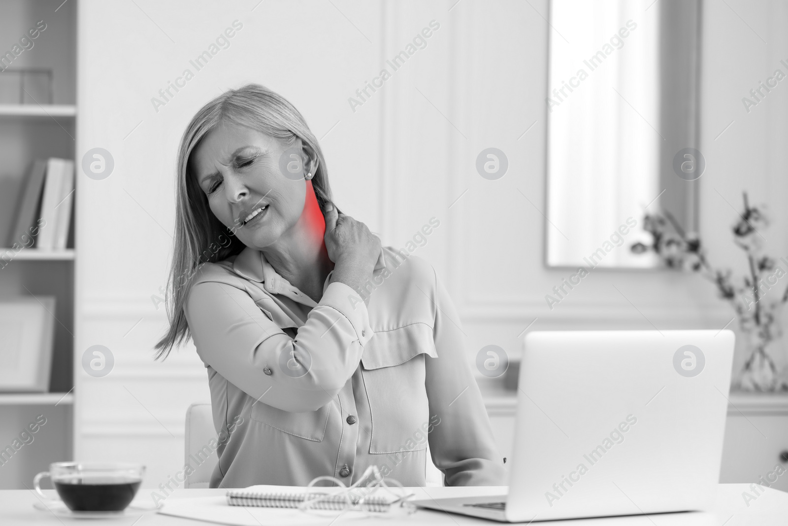 Image of Woman suffering from neck pain at table, black and white effect