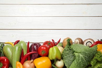 Photo of Different fresh vegetables on white wooden table, flat lay. Space for text