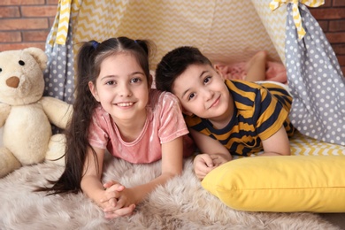 Playful little children in handmade tent indoors