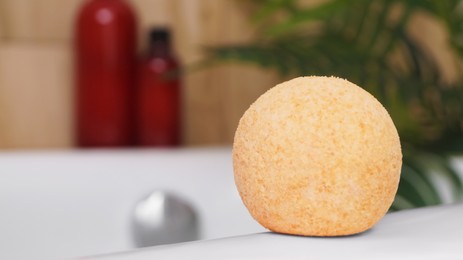 Orange bath bomb on tub indoors, space for text