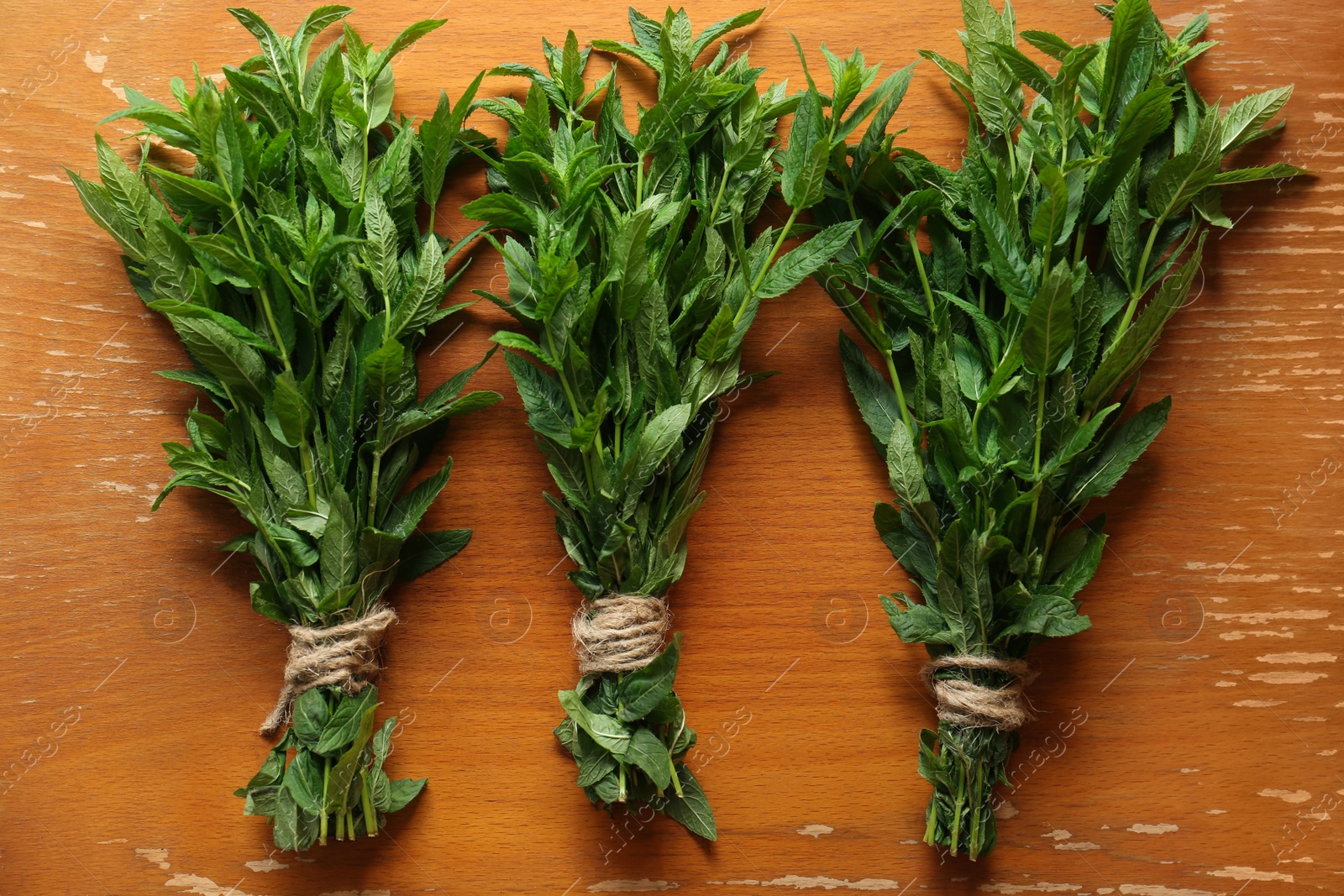 Photo of Bunches of beautiful green mint on brown wooden table, flat lay