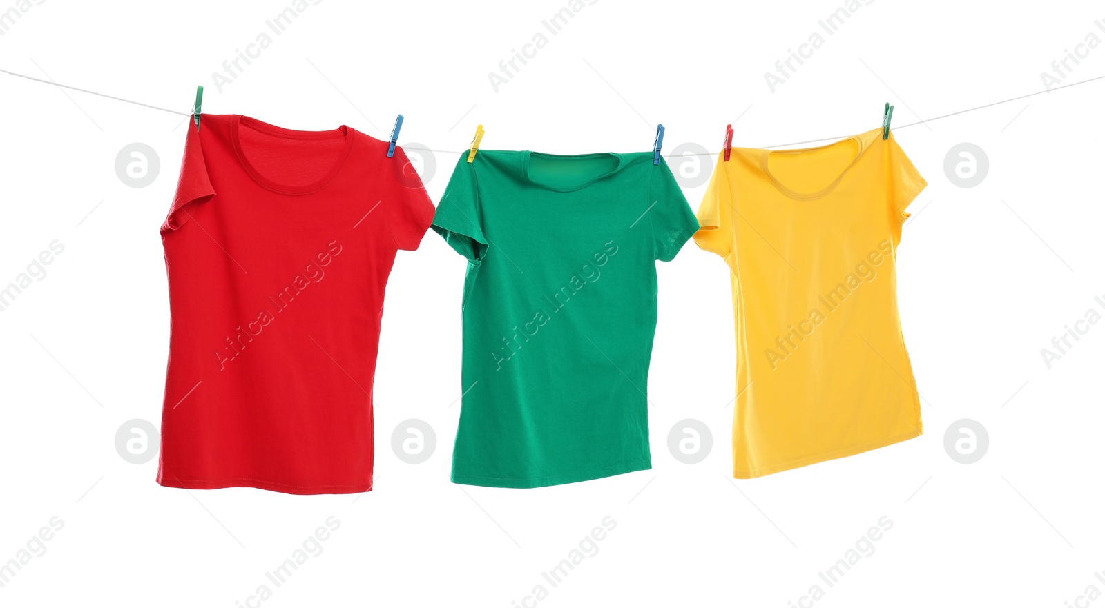 Photo of Different bright t-shirts drying on washing line against white background