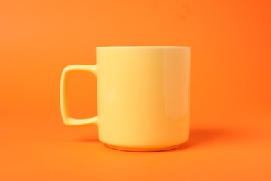 Photo of One yellow ceramic mug on orange background