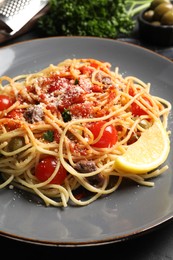 Photo of Delicious pasta with anchovies, tomatoes and parmesan cheese on table, closeup