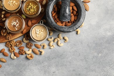 Photo of Making nut butters from different nuts. Flat lay composition with space for text on light grey table