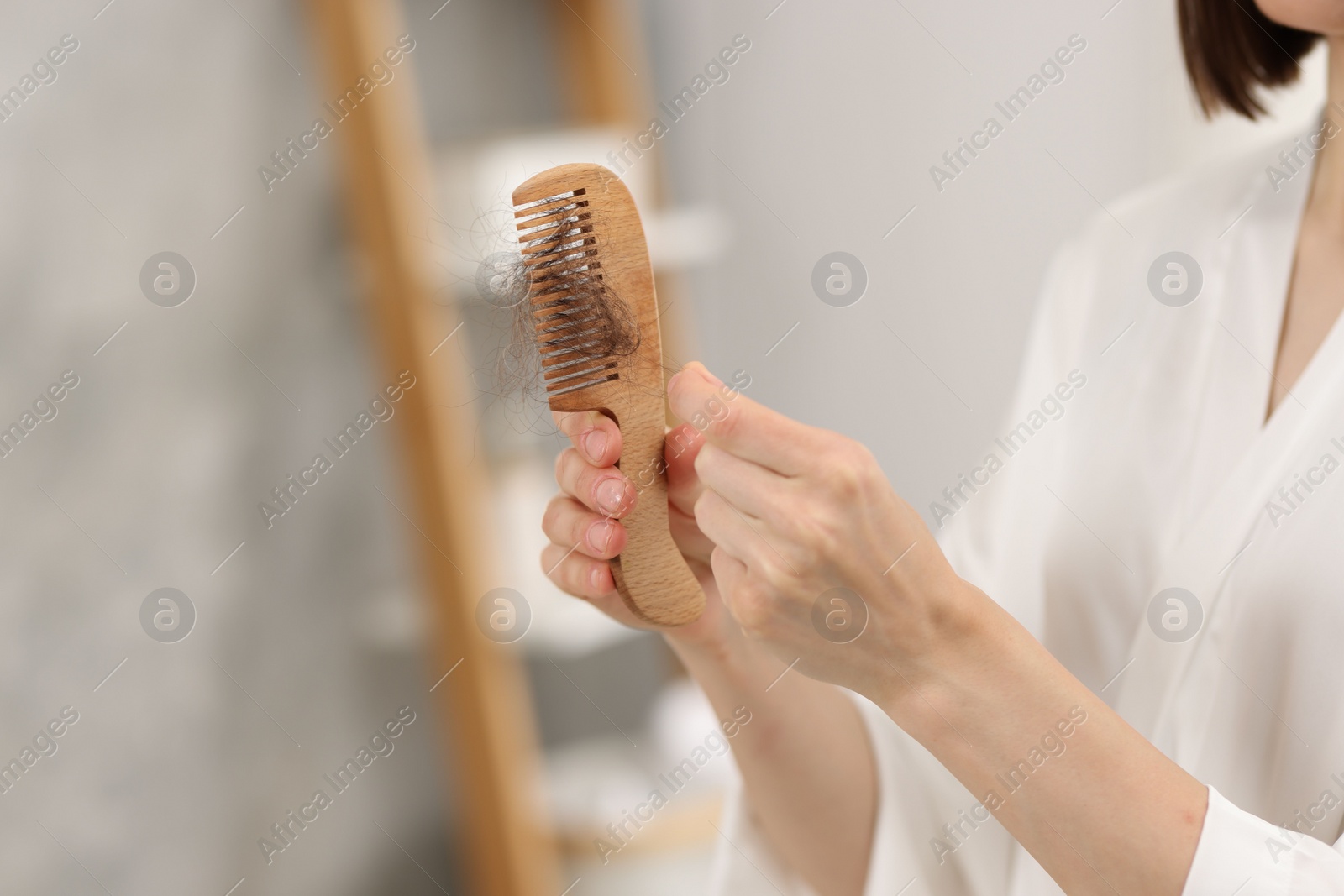 Photo of Woman taking her lost hair from comb at home, closeup. Alopecia problem