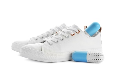 Photo of Sneakers with capsule shoe fresheners on white background