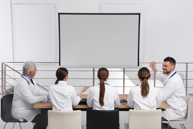 Team of doctors using video projector during conference indoors