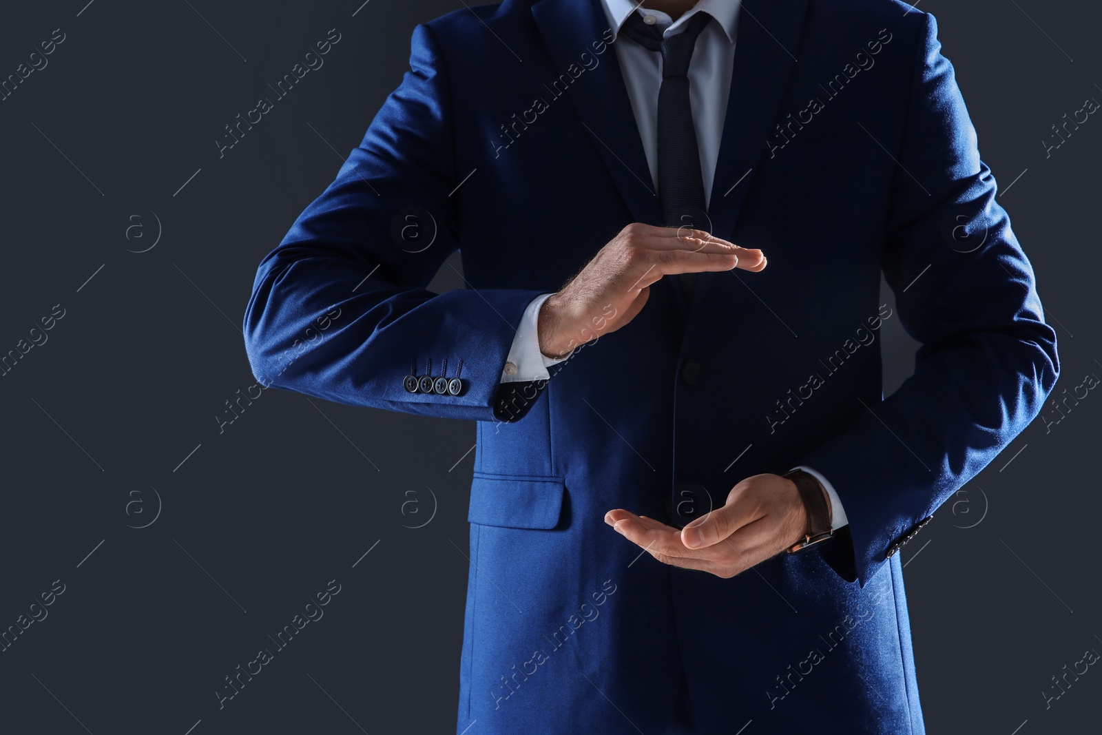 Photo of Businessman holding something in hands on dark background