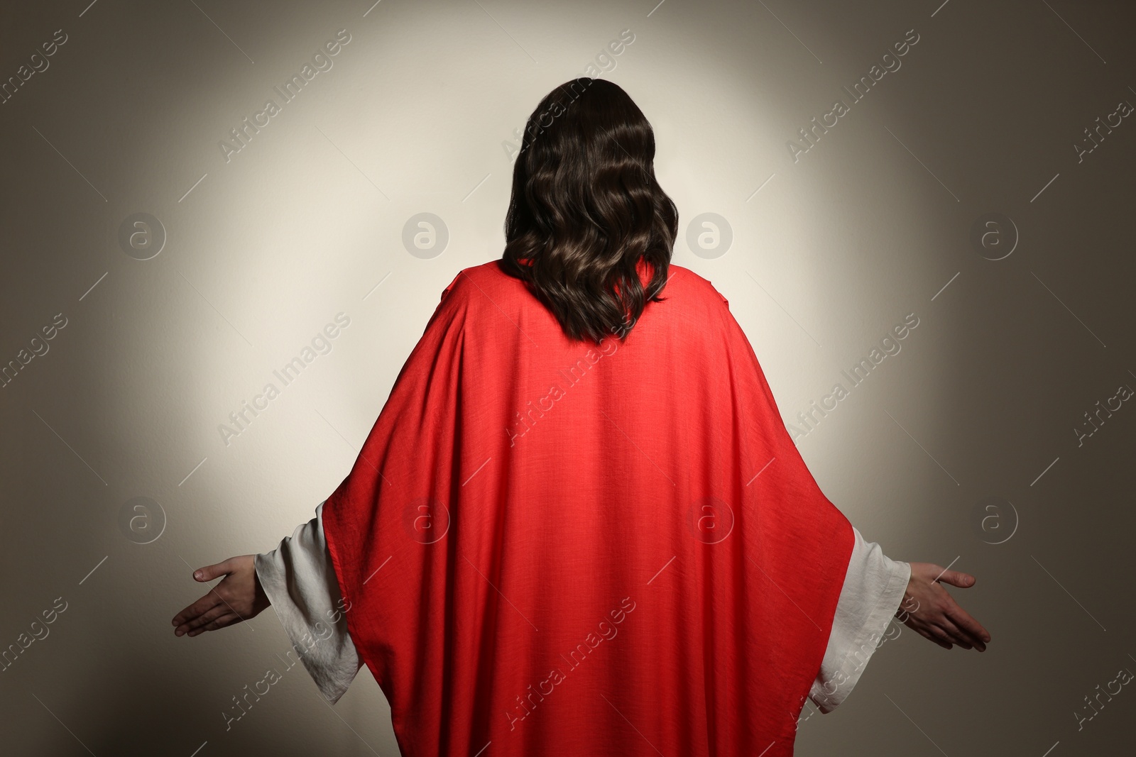 Photo of Jesus Christ with outstretched arms on beige background, back view