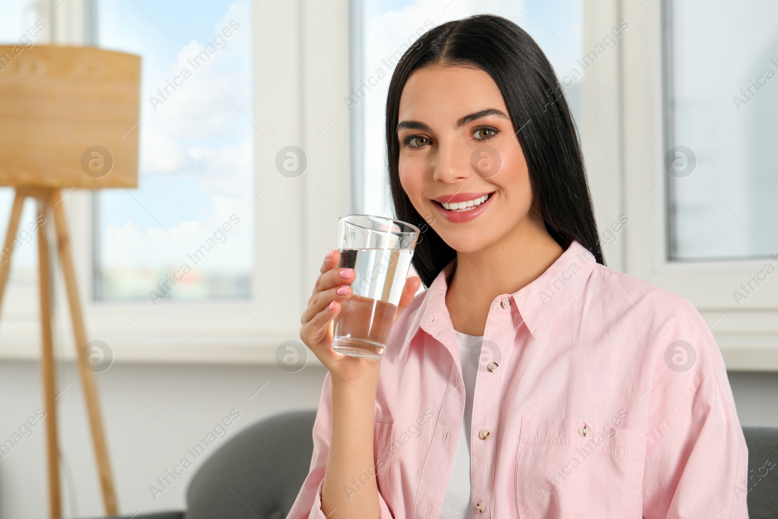 Photo of Young woman with glass of water indoors. Refreshing drink