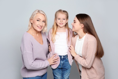 Portrait of young woman, her daughter and mature mother on color background