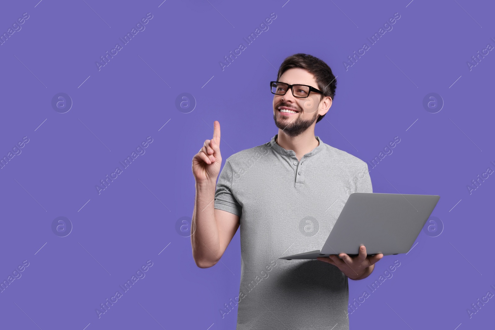 Photo of Happy man with laptop on lilac background, space for text