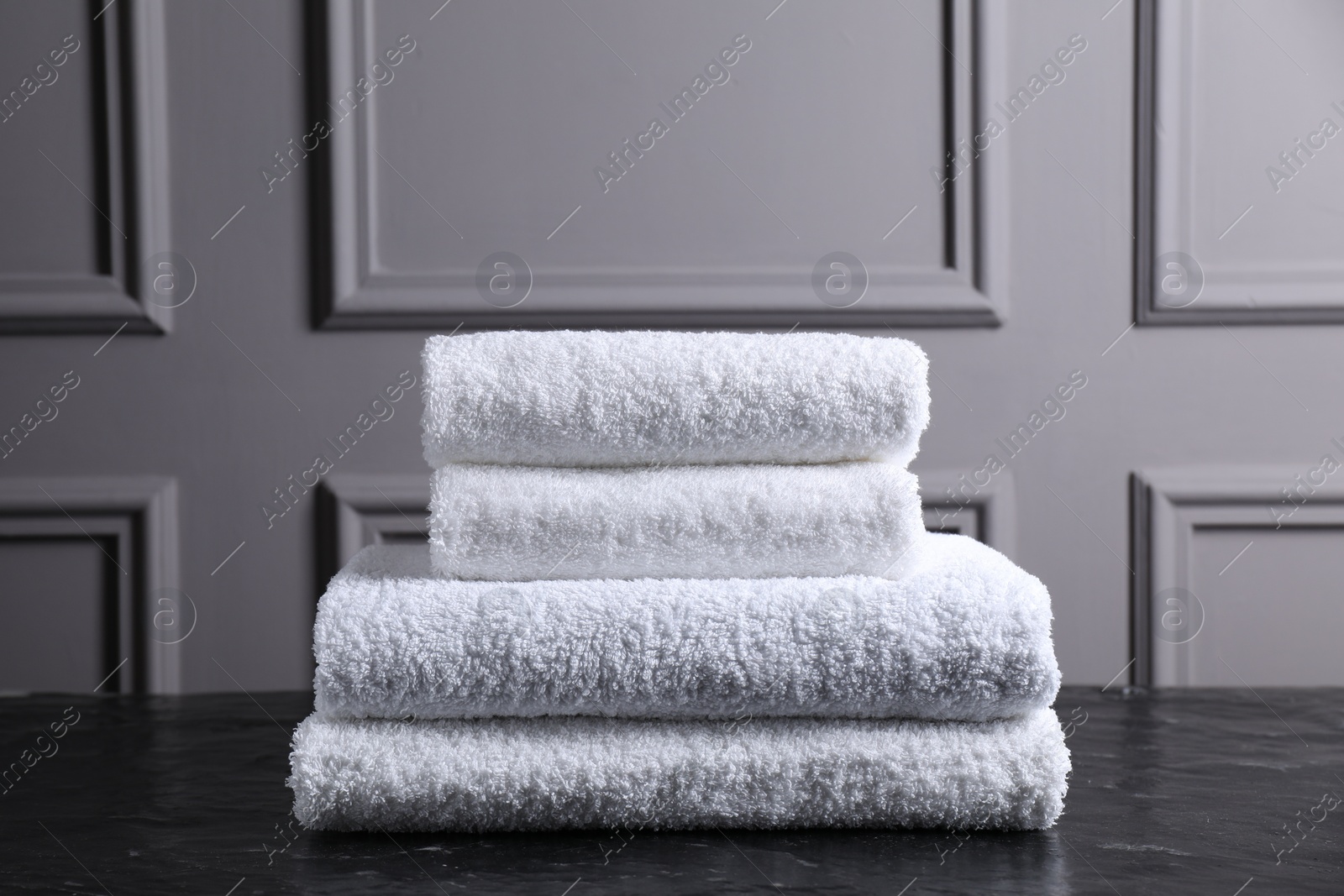 Photo of Stacked terry towels on black textured table indoors