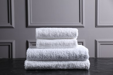 Photo of Stacked terry towels on black textured table indoors